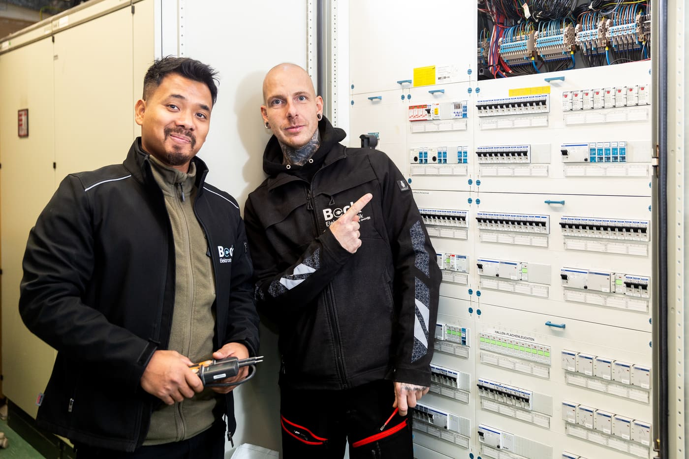 Zwei Elektriker besprechen die Verteilung im Technikraum